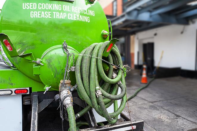 worker pumping grease trap at commercial kitchen in Clark Mills, NY